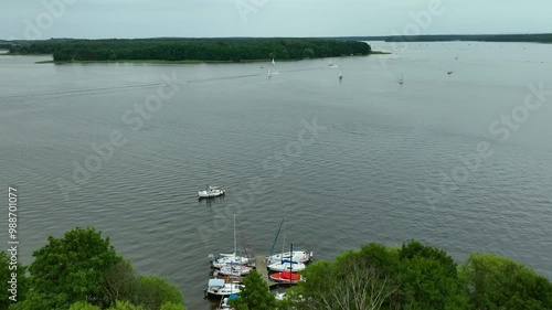 Aerial view of a marina on Jeziorak Lake in Siemiany, Poland, with boats docked near the shoreline and a wide expanse of water leading to distant islands photo