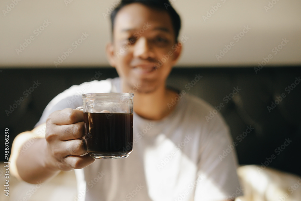Asian man enjoy drinking coffee on the bed after wake up from sleep Asian man enjoy drinking coffee on the bed after wake up from sleep