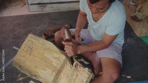 A Balinese artist expertly carve a Barong mask using a chisel and mallet. Captures the traditional techniques and artistry behind Bali's iconic cultural symbol. Ubud, Bali. photo