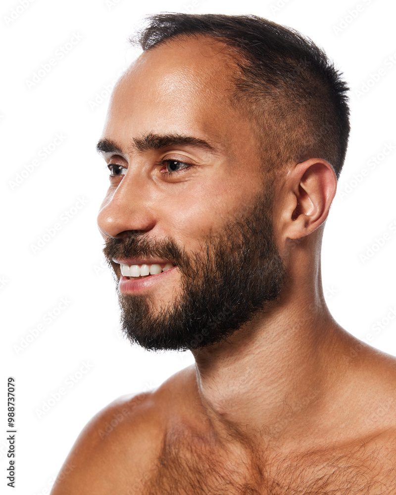 Obraz premium Close-up portrait of handsome young bearded man with tanned, spotless, clear skin, smiling, posing isolated on white studio background. Concept of male beauty, skin care, hygiene, health