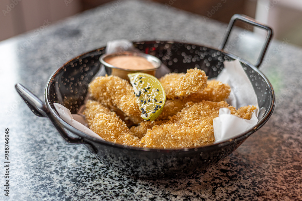 golden deep-fried battered chicken nuggets.succulent chicken chunks ensconced in a delectable batter, crisped up with Panko, and draped in sauce closeup on the plate on the table. golden deep-fried battered chicken nuggets.succulent chicken chunks ensconced in a delectable batter, crisped up with Panko, and draped in sauce closeup on the plate on the table.