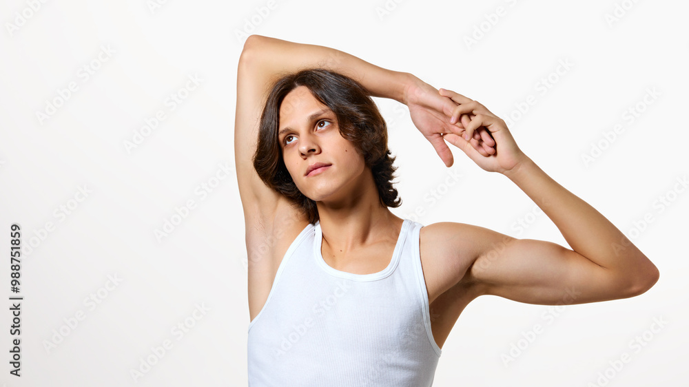Calm young man stretching his hands and looking upwards against white studio background. Morning exercises. Concept of natural beauty, fashion, cosmetic product, male health. Ad Calm young man stretching his hands and looking upwards against white studio background. Morning exercises. Concept of natural beauty, fashion, cosmetic product, male health. Ad