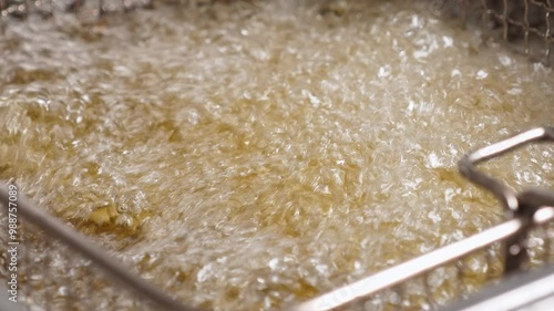 Close-up of deep-fried boiling oil in the restaurant kitchen. The process of cooking various fried snacks in an industrial kitchen. Fast food.