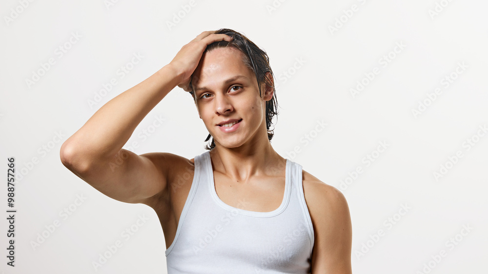 Man looking with confidence at camera while grabbing his wet, clean hair after bath treatment against white studio background. Concept of natural beauty, fashion, cosmetic product, male health. Ad Man looking with confidence at camera while grabbing his wet, clean hair after bath treatment against white studio background. Concept of natural beauty, fashion, cosmetic product, male health. Ad