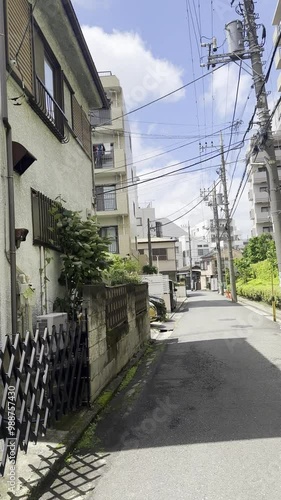 Strolling through a quiet, narrow street in Japan, surrounded by residential buildings that reflect everyday life in the city. A peaceful glimpse into local living. photo