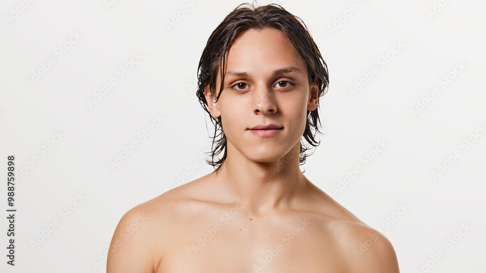 Obraz premium Portrait of young attractive brunette man with wet hair posing shirtless against white studio background. Concept of natural beauty, fashion, cosmetic product, male health. Ad