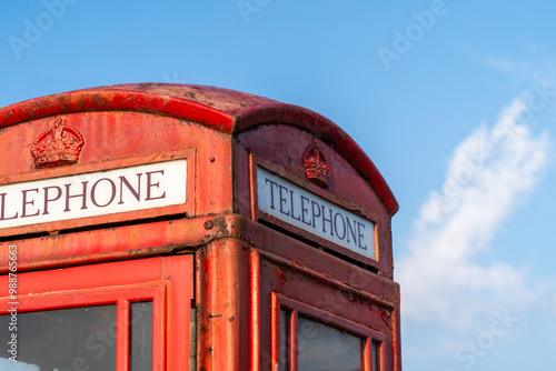 Traditional old red telephone box close up in England, United Kingdom with blue sky background