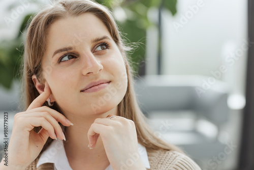 A beautiful young girl in the office works with documents, holds a pen in her hand and looks at the camera.