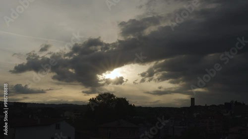 timelapse of Clouds advancing across the sky on the outline of a tree and a tower as the sun sets and creates beautiful lighting effects 