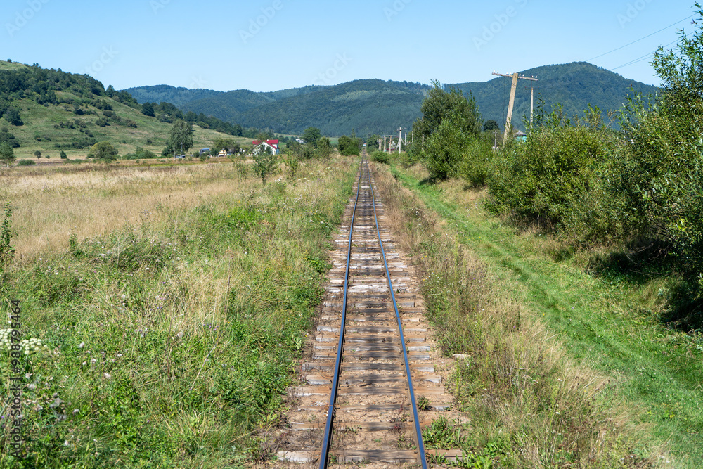 Narrow gauge railway in a mountain village. Rails and sleepers. Railway track. Nature in summer. Travel by train. Carpathians green grass Narrow gauge railway in a mountain village. Rails and sleepers. Railway track. Nature in summer. Travel by train. Carpathians green grass