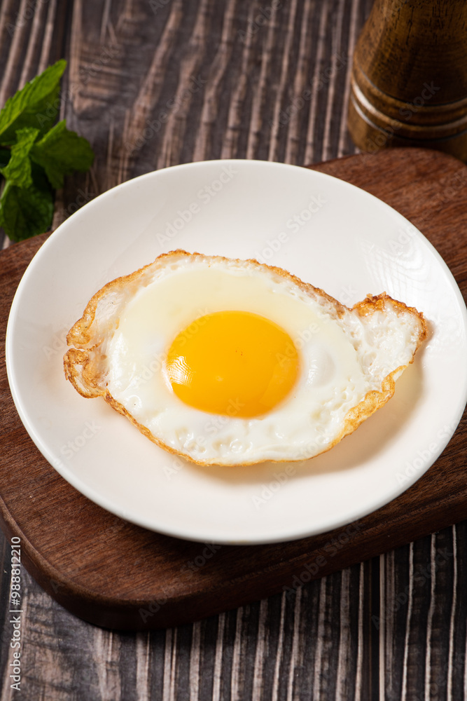 fried egg in a white plate on table. fried egg in a white plate on table.