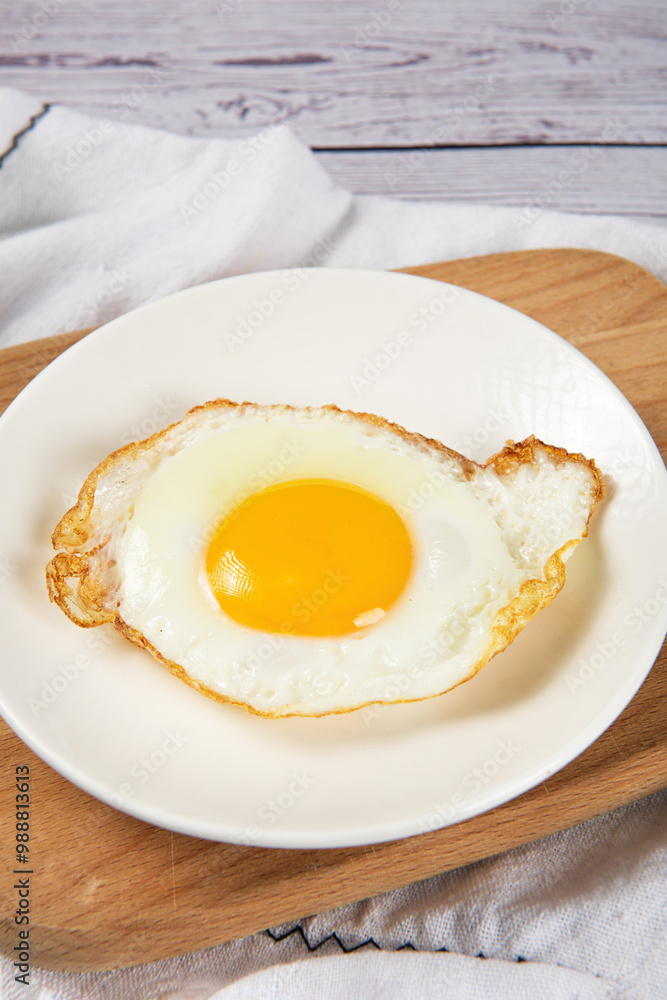 fried egg in a white plate on table. fried egg in a white plate on table.