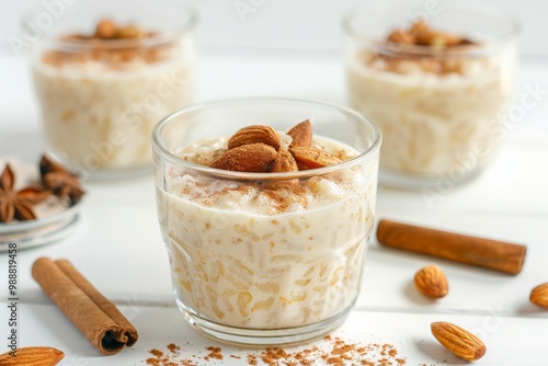 Creamy rice pudding topped with cinnamon and almond, white wooden background, MZ