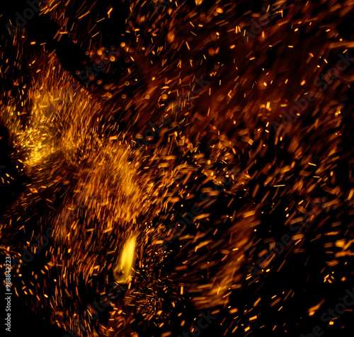 The image is a close up of a fire with a lot of sparks flying out of it