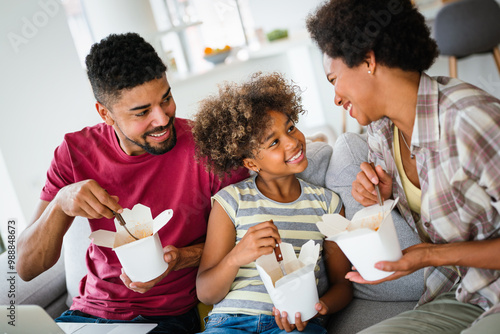 Happy african family eating at living room and enjoying time together. Home delivary takeaway food photo