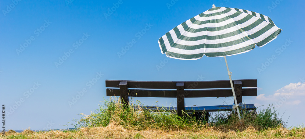 Panorama of a bench and parasol on top of the dike in Termunterzijl, Netherlands