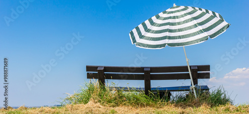 Obraz na płótnie Panorama of a bench and parasol on top of the dike in Termunterzijl, Netherlands w salonie