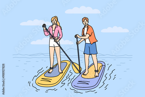 Surfing on SUP boards is practiced by man and woman using paddles to navigate river on summer weekend. Man and woman surfers stand on SUP boards, engage in active recreation at hot resort