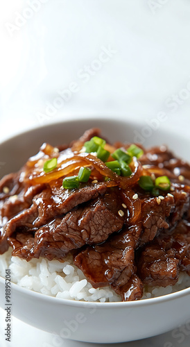 Gyudon, a bowl of rice topped with savory beef, drizzled in a rich sauce and garnished with green onions.