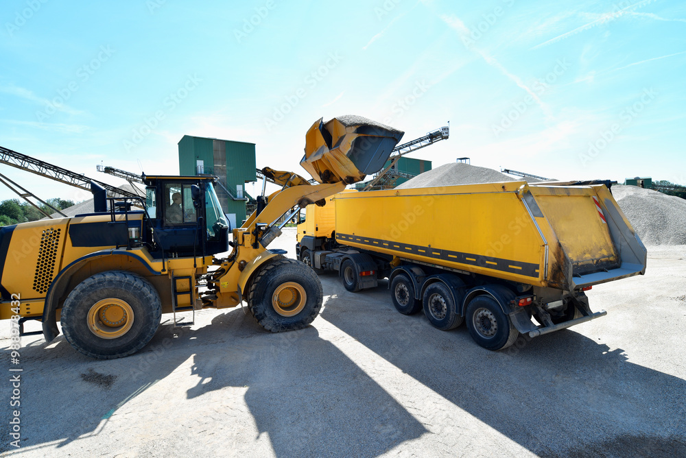 Wheel loader loads a truck with sand in a gravel pit Wheel loader loads a truck with sand in a gravel pit