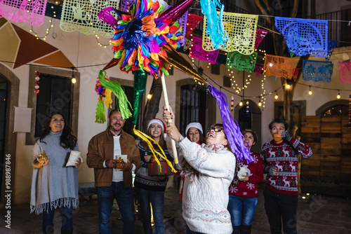 Tableau sur toile Mexican woman and family breaking a piñata at traditional posada party for Chris