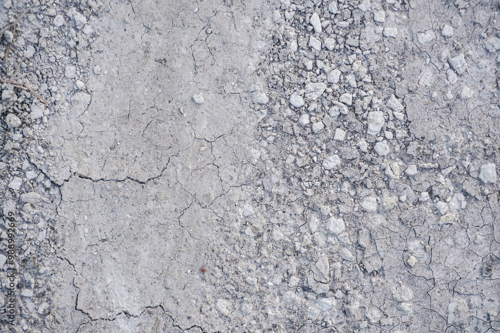 close-up of a textured dry soil surface with small stones or gravel scattered on a light gray ground close-up of a textured dry soil surface with small stones or gravel scattered on a light gray ground