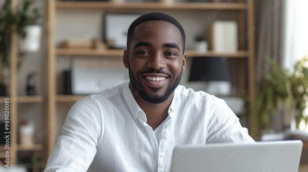 Portrait of smiling man sitting at desk with laptop looking in camera Portrait of smiling man sitting at desk with laptop looking in camera
