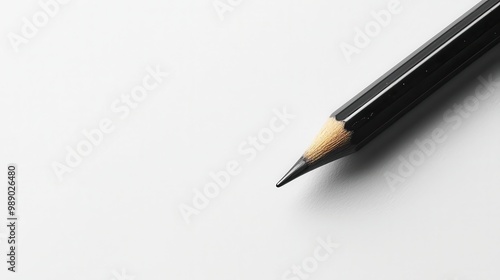 A close-up of a sharpened black pencil resting on a clean white surface, ideal for artistic and educational themes.