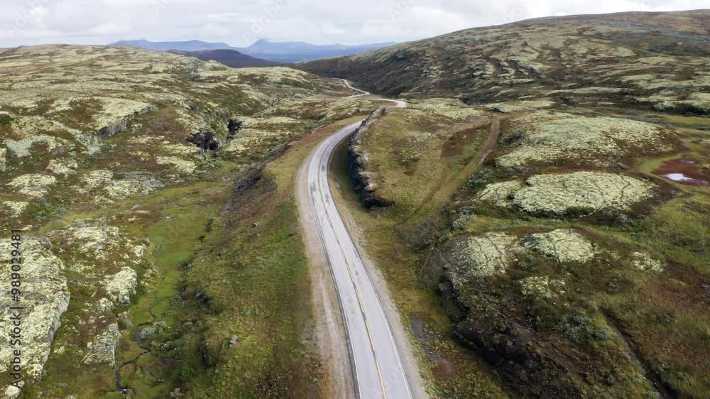 Road leading throught Norvegian severe Tundra nature with birdsyey top view. Picturesque northern Norway landscape and modern highway construction aerial 4K video. Rondane National Park, Norway.