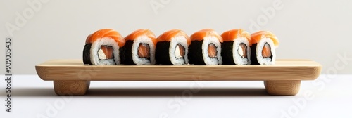 A minimalist design of a sushi plate featuring maki rolls, arranged neatly on a wooden board with a white backdrop photo