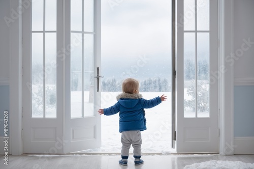 Toddler observing snowy landscape from inside home