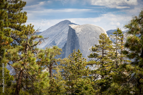 Iconic view of Half Dome from the Sentinel Dome trail in Yosemite National Park, California, showcasing a rugged granite landscape framed by pine trees. photo