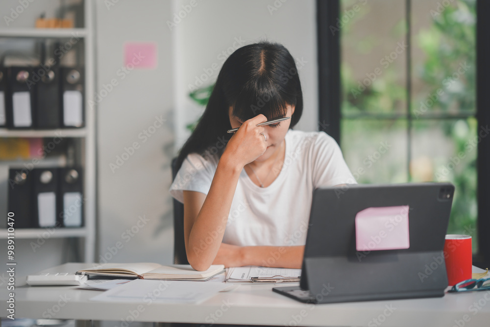 Young asian accountant is feeling tired and having a headache while working from home Young asian accountant is feeling tired and having a headache while working from home