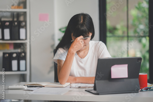 Young asian accountant is feeling tired and having a headache while working from home