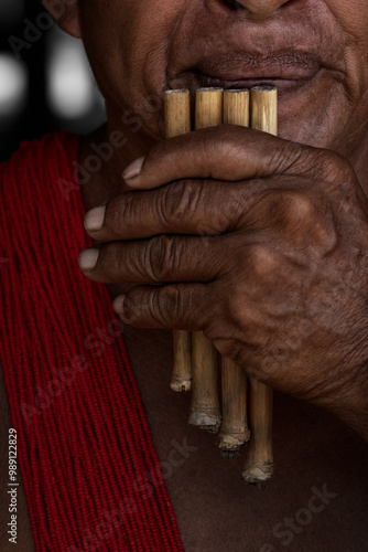 Elderly man playing a pan flute in the native village of Paloemeu in the Amazonian rainforest of Suriname photo