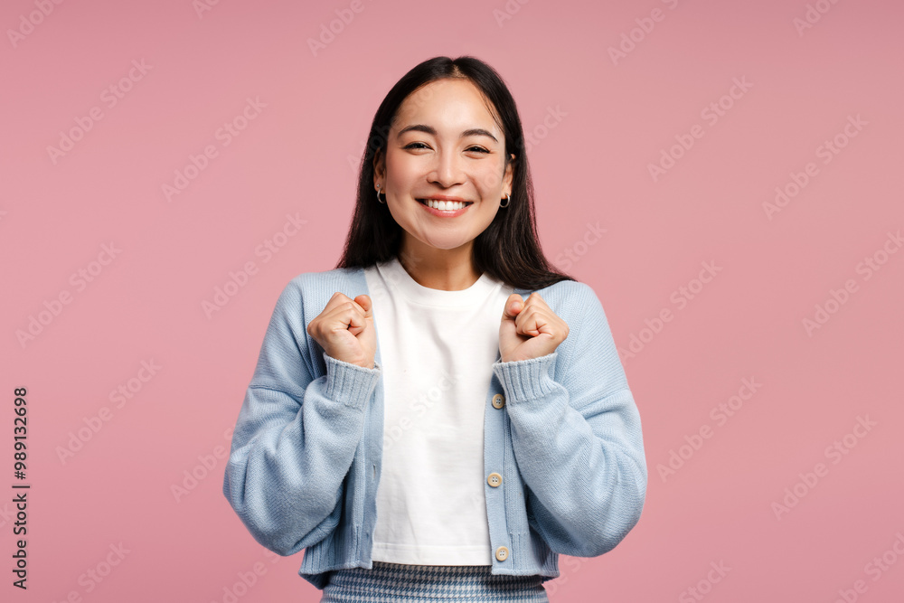 Smiling Asian woman smiling and cheering with fists up posing on pink background. Victory concept Smiling Asian woman smiling and cheering with fists up posing on pink background. Victory concept