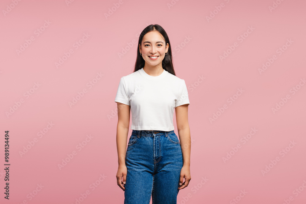 Smiling, attractive Asian woman smiling wearing white t-shirt and jeans on pink background Smiling, attractive Asian woman smiling wearing white t-shirt and jeans on pink background