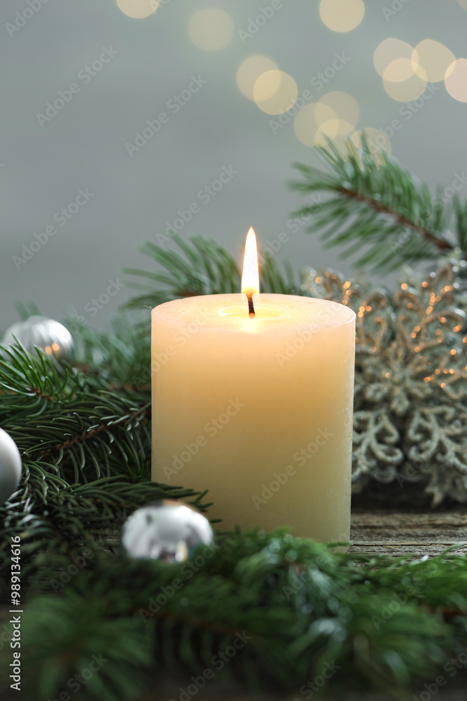 Burning candle, baubles and fir tree branches on wooden table, closeup Burning candle, baubles and fir tree branches on wooden table, closeup