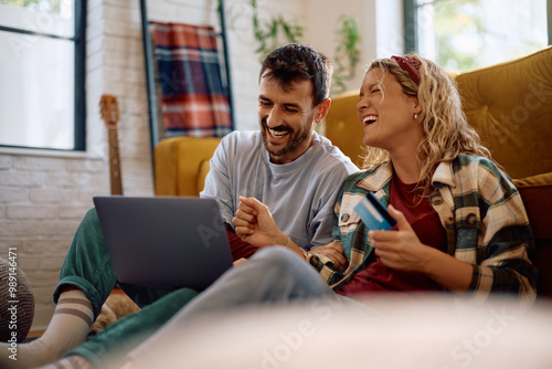 Foto Cheerful couple shopping online while relaxing at home.