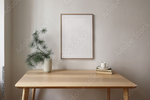 Christmas Scandinavian interior. Minimal winter home decor composition. Blank vertical wooden picture frame mockup hanging on beige wall. Cup of coffee, tea. Pine tree branches, vase on wooden table.