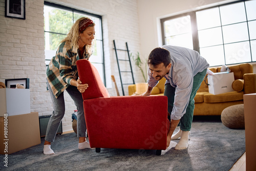 Happy couple carrying armchair into their new living room. photo