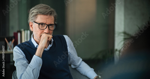 Professional marriage counselor sits in chair, talks and listens attentively to patients during consultation. Mature psychologist analyzes problem, provides couples therapy. Psychological assistance.