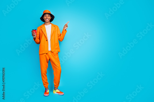 Photo of stylish guy standing hold cooffee cup demonstrate empty space text for ads isolated cyan color background photo