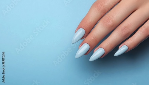 Pastel blue manicure on a female hand with blue background. Close-up. Nail art wallpaper