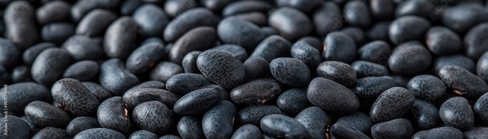 Close-up of black beans scattered on a surface, showcasing their shiny texture and rich color, ideal for culinary themes. Close-up of black beans scattered on a surface, showcasing their shiny texture and rich color, ideal for culinary themes.