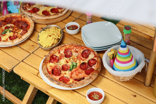 Pizza at a birthday party. Close up photo with salami diavola pepperoni pizza on a wooden table during a backyard garden celebration. photo