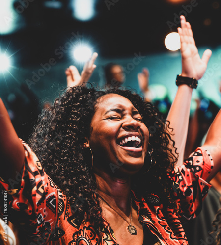 African American woman worshipping God in her church with her eyes closed and her arms in the air in praise