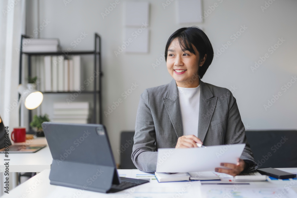 Asian businesswoman is smiling while working on documents in her modern office Asian businesswoman is smiling while working on documents in her modern office