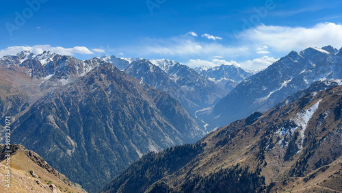 High massive mountains covered with forest and glaciers at the peak