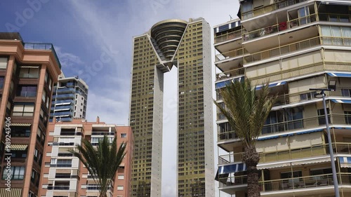 Gimbal Shot of the Intempo Skyscraper in Benidorm, Spain Tallest Building in Costa Blanca camera movement towards the golden 
tower from beach Street View with houses Palm Trees and Blue Sky 4K HQ